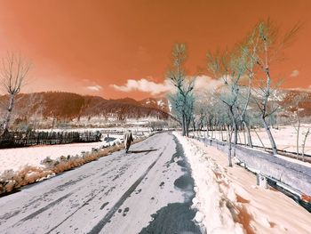 Snow covered field against sky during winter