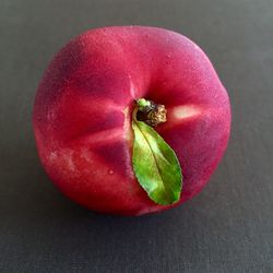 Close-up of a red peach over natural gray background
