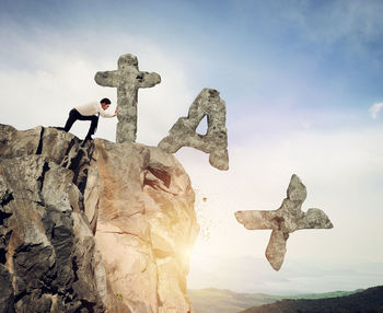 Cross on rock against sky