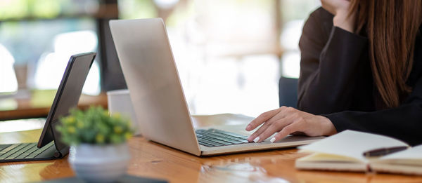 Midsection of woman using laptop on table