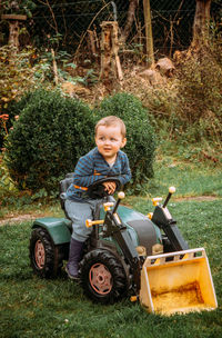 Portrait of cute boy smiling while sitting by plants