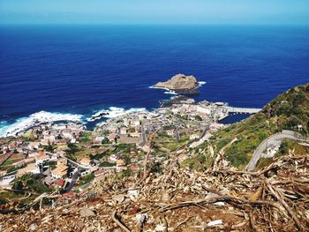 High angle view of townscape by sea against blue sky