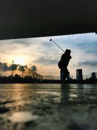 Silhouette man standing on shore against sky during sunset