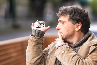 Close-up of man holding model house in city