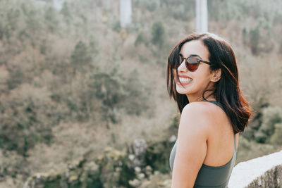 Portrait of young woman wearing sunglasses standing on field