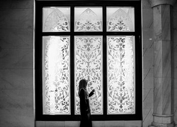 Woman standing by window at home