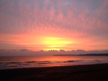 Scenic view of sea against cloudy sky at sunrise