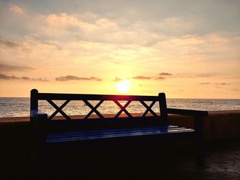 Silhouette railing by sea against sky during sunset