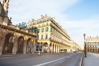 Road by buildings against sky in city