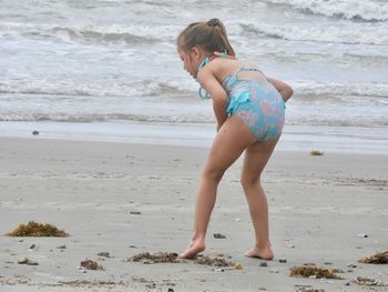 Full length of girl playing on sand against sea at beach