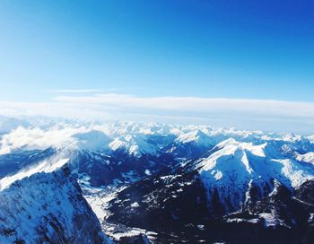 Scenic view of snowcapped mountains against blue sky