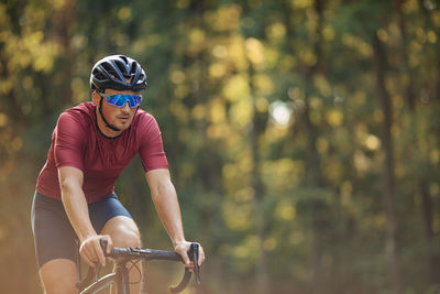 Muscular young man in activewear enjoying bike riding on fresh air. 