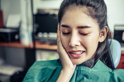 Young woman sitting at dentist clinic with toothache