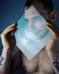 Portrait of young man holding camera over gray background