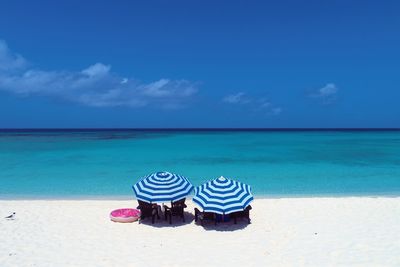 Deck chairs on beach against sky