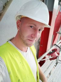 Portrait of smiling young man wearing hardhat at construction site