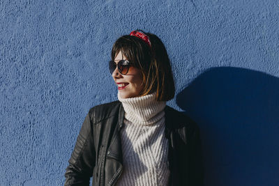 Portrait of smiling young woman against wall