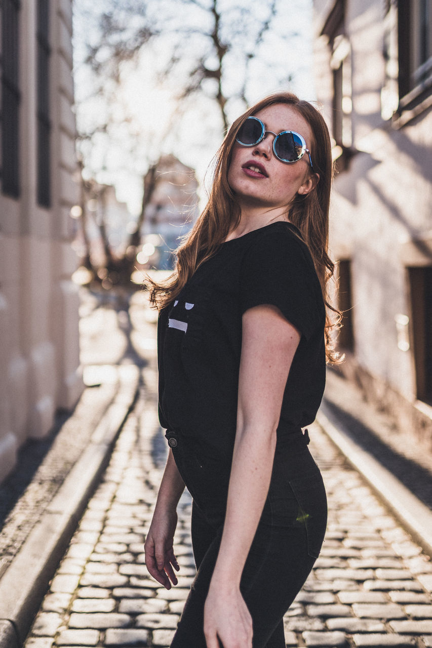 fashion, young adult, one person, young women, sunglasses, architecture, women, focus on foreground, lifestyles, hairstyle, long hair, real people, glasses, adult, side view, beauty, leisure activity, hair, beautiful woman, track, outdoors