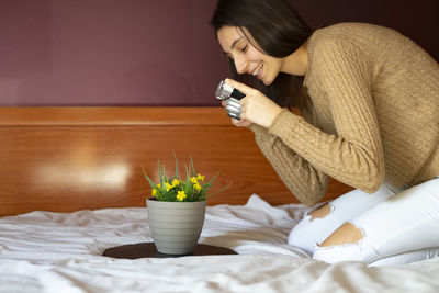 Woman holding ice cream on bed at home