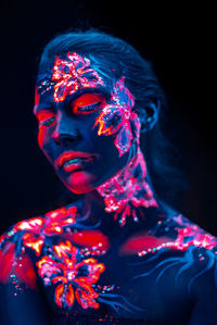 Young woman with paint on her body against black background