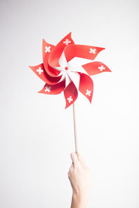 Close-up of hand holding pinwheel toy against white background