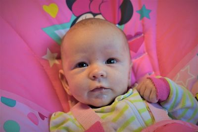 Portrait of cute baby girl lying on bed