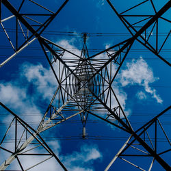 Low angle view of electricity pylon against blue sky