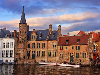 Buildings by river against sky