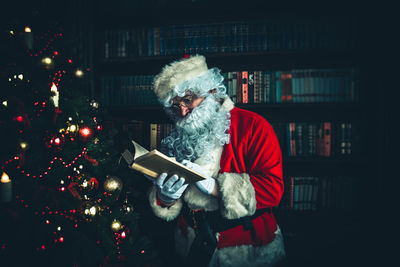 Man wearing santa claus costume reading book at home