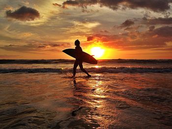 Silhouette of people on beach at sunset