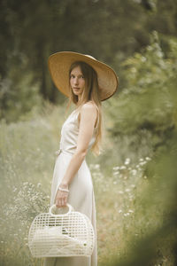 Portrait of young woman wearing hat standing in basket
