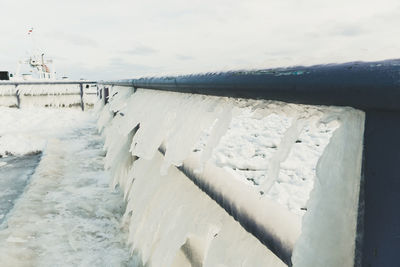 Snow covered railing against sky