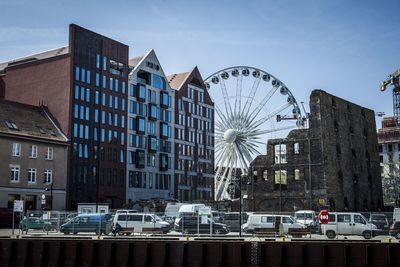 Ferris wheel by buildings in city against sky