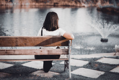 Rear view of woman sitting on bench