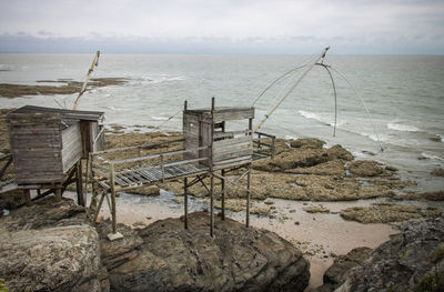 Scenic view of sea and fishing hut against sky