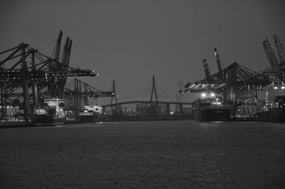 Cranes at commercial dock against clear sky at night