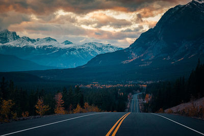 Road leading towards mountains against sky