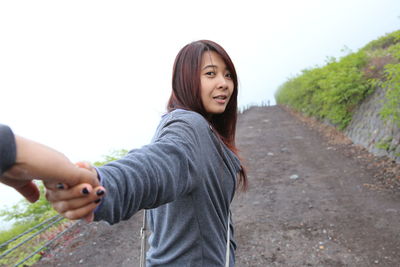 Portrait of young woman standing against sky