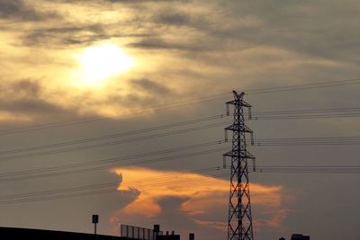 Low angle view of electricity pylon against cloudy sky