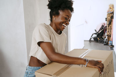 Happy woman holding cardboard box at new home