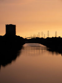 Silhouette bridge over river against sky during sunset
