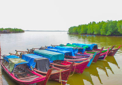 Multi colored boats moored in lake against clear sky