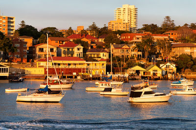 Sailboats moored on sea against buildings in city