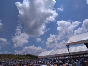 Group of people at music concert against cloudy sky