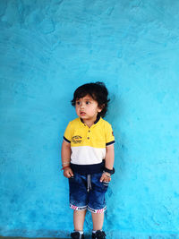 Boy standing against blue wall