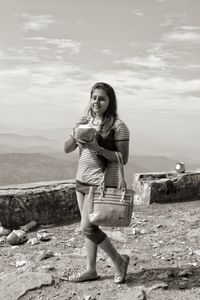 Portrait of smiling young woman standing against sky