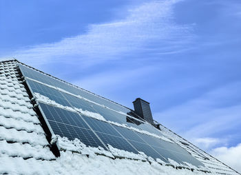 Solar panels producing clean energy on a snow coevered roof of a residential house