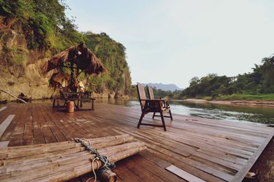 Chairs and table against trees on landscape against sky