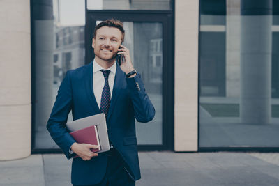 Portrait of young man standing against building