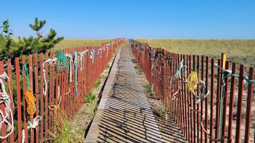Wooden fence on field against clear blue sky